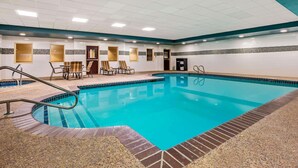 Una piscina con bordi piastrellati, una zona relax con sedie e una porta sullo sfondo.