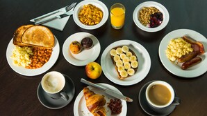 A breakfast table with various dishes including toast, beans, muffins, bananas, sausages, and coffee. - Holiday Inn Express East Midlands Airport by IHG (Derby)