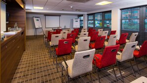 A conference room with rows of chairs, a whiteboard, and a presentation screen. - Holiday Inn Express East Midlands Airport by IHG (Derby)