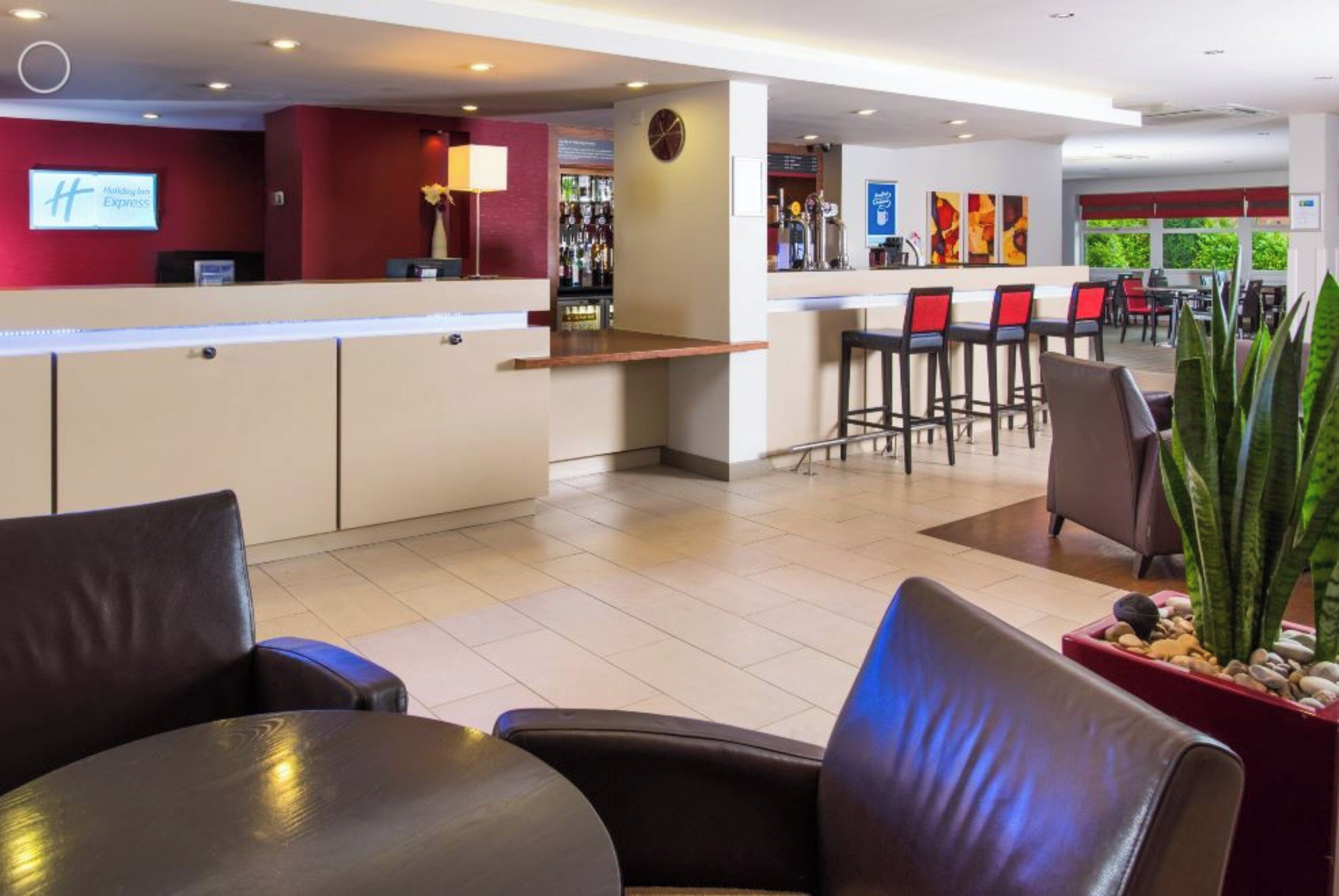 A hotel lobby with a reception desk, a bar area, and seating arrangements.
