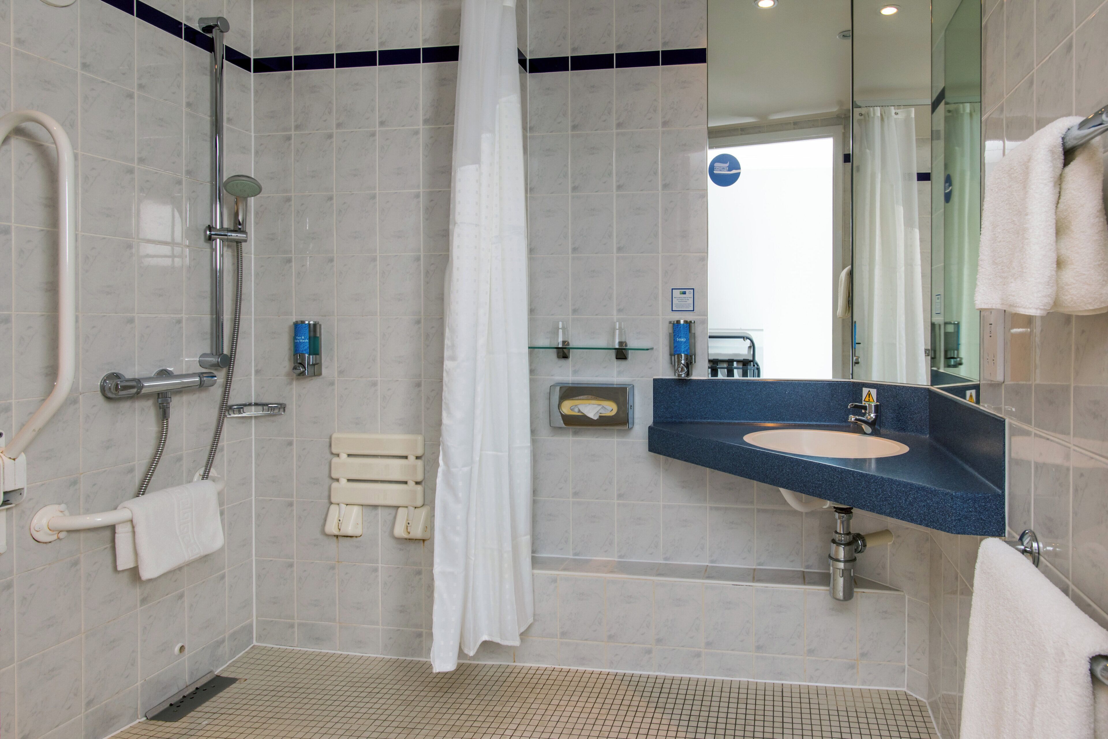 Un bagno moderno con doccia, lavandino e specchio.