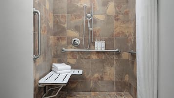 A shower area with a grab bar, a shelf with toiletries, and a white towel.