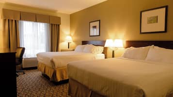 Ein Hotelzimmer mit zwei Betten, einem Schreibtisch und einem Sessel. Auf beiden Seiten der Betten stehen jeweils Lampen.