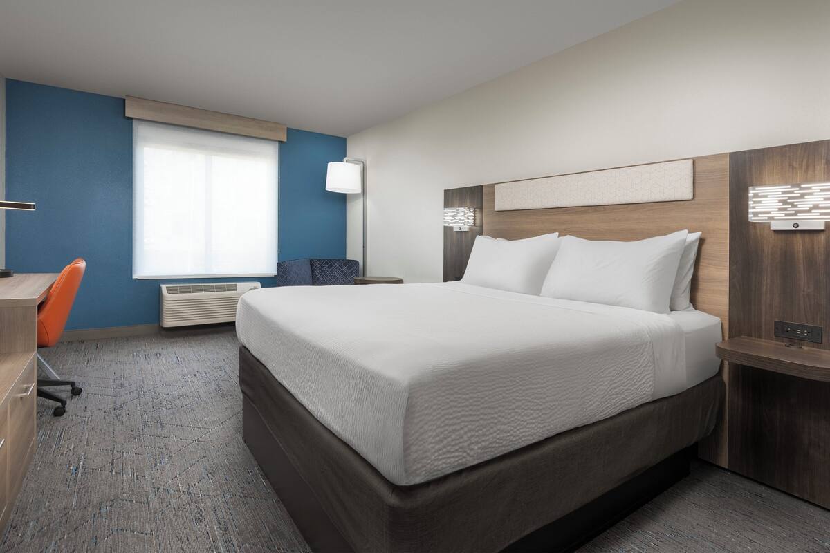 Une chambre d’hôtel moderne, dotée d’un grand lit, d’un bureau et d’une chaise.