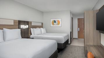 Een hotelkamer met twee bedden, een flatscreen televisie en een deur die naar een andere kamer leidt.