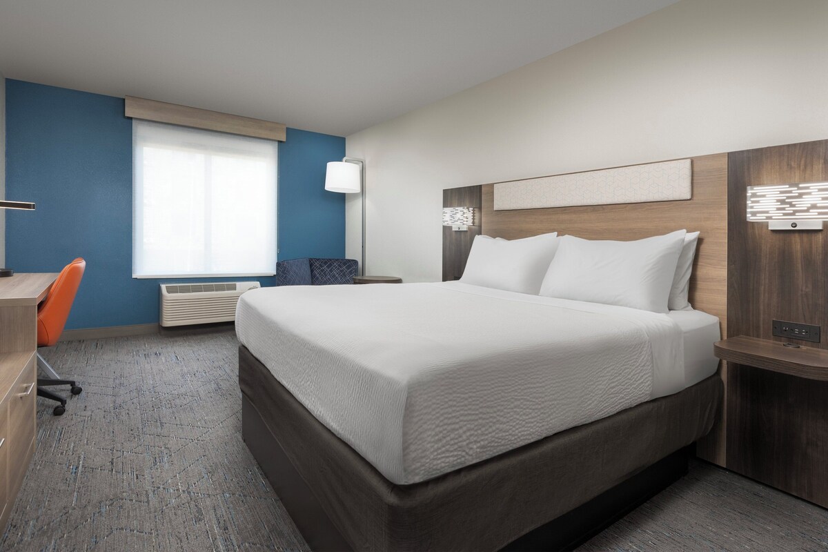 Quarto de hotel moderno com uma cama grande, uma escrivaninha e uma cadeira.