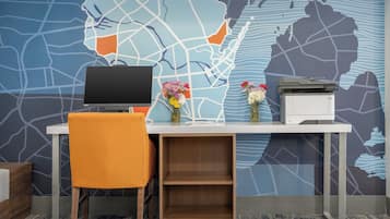 A desk with a computer, a printer, and a vase with flowers.