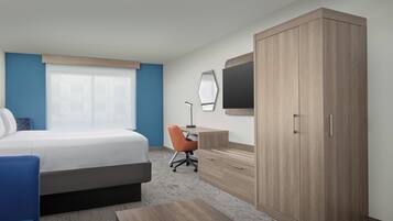 A hotel room with a bed, a desk, a chair, a wardrobe, and a television.