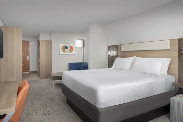 Quarto de hotel com uma cama grande, uma escrivaninha e uma cadeira.