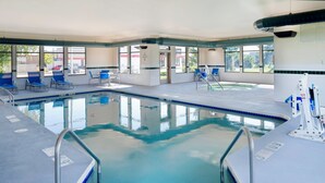 An indoor swimming pool with clear blue water, surrounded by lounge chairs and a poolside area.
