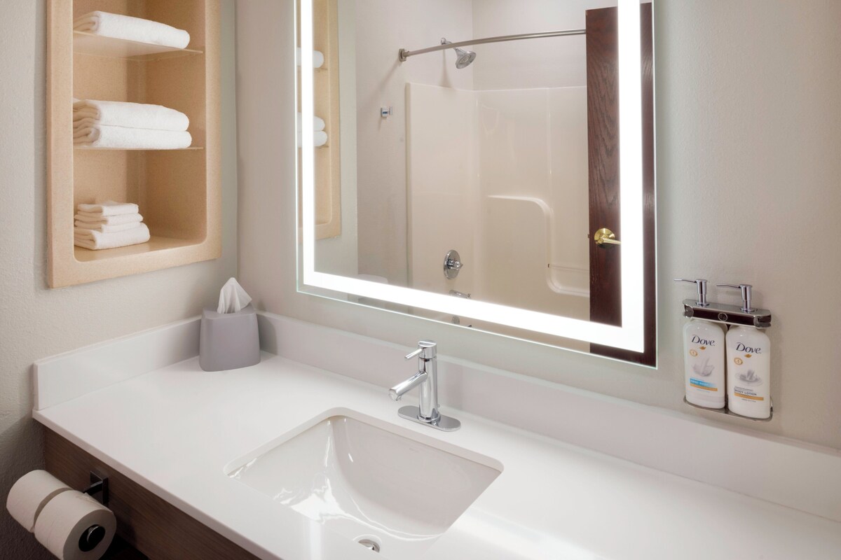 A bathroom with a white sink, a mirror, a towel rack, and a shower door.