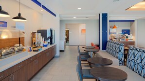 Un moderno vestíbulo de hotel con una larga recepción, zona de estar y una kitchenette.