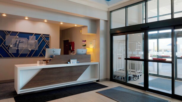 A reception area with a modern desk, a large window, and a view of the airport outside.