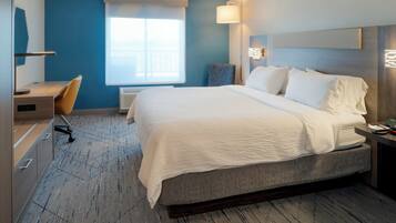 A hotel room with a large bed, a desk, and a chair.