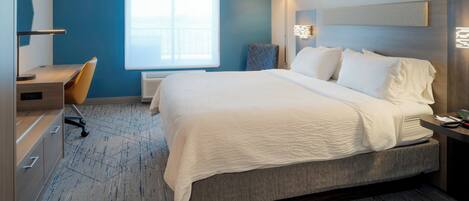 A hotel room with a large bed, a desk, and a chair.