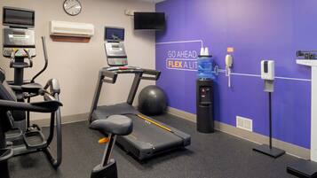 A fitness room with exercise equipment, a water dispenser, and motivational wall text.