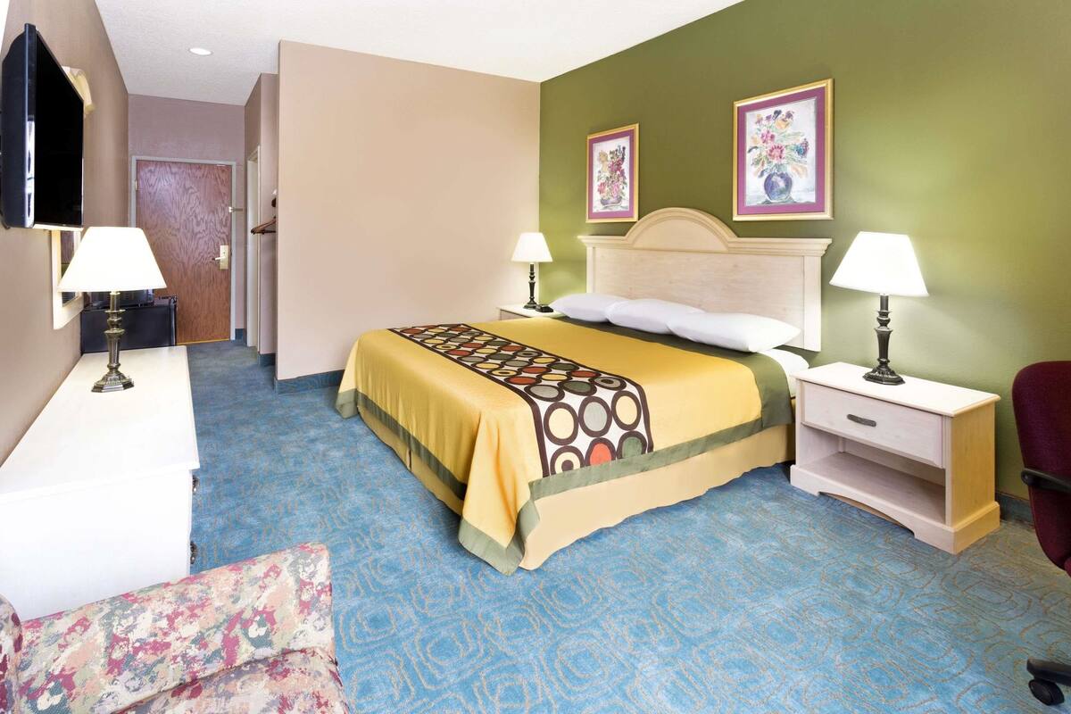 A hotel room with a bed, two bedside tables with lamps, a chair, and a desk.