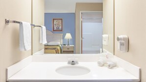 A bathroom with a white sink, a mirror, and a towel rack. - Super 8 by Wyndham Freeport (Freeport)