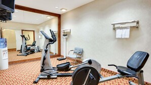 A hotel gym with exercise equipment, a mirror, and a towel rack. - Super 8 by Wyndham Freeport (Freeport)