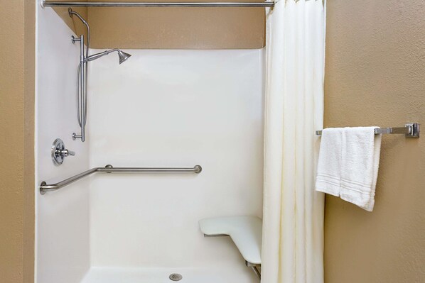 A shower with a grab bar, a white towel, and a shower curtain.
