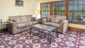 A living room with two beige sofas, a patterned rug, and a coffee table. - Super 8 by Wyndham Freeport (Freeport)