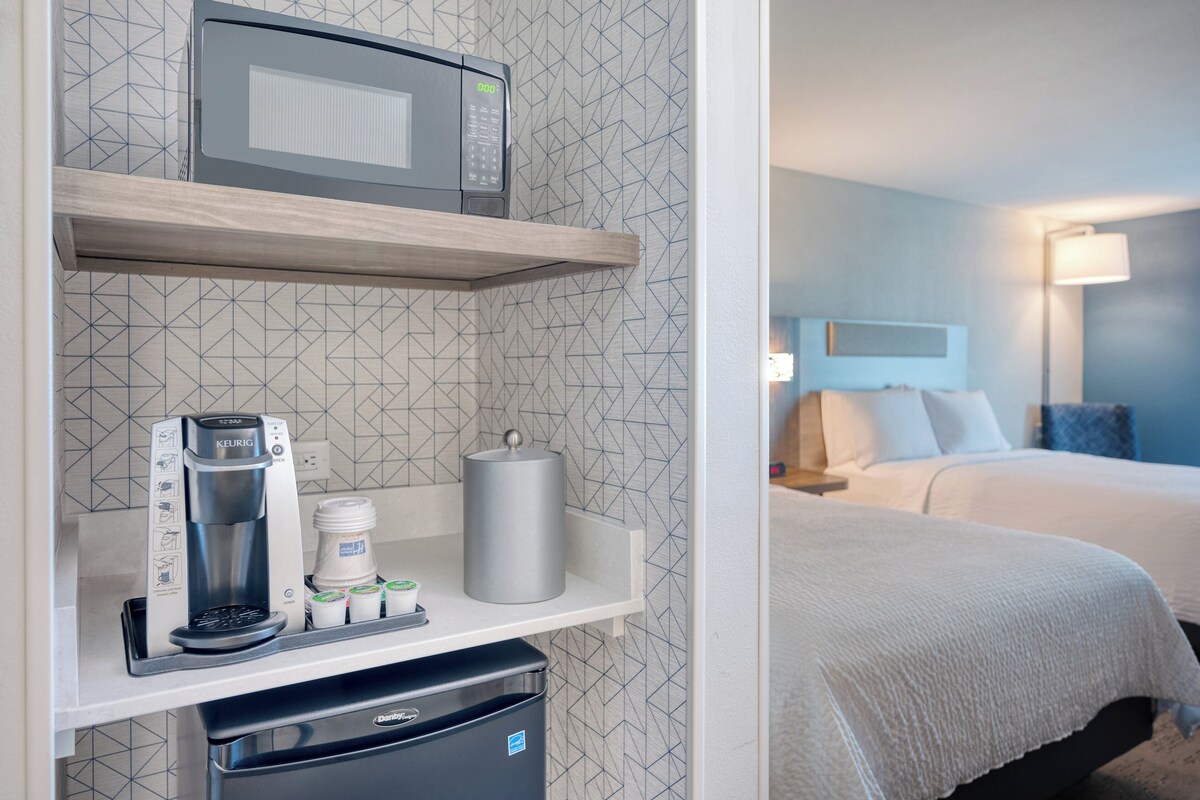 A kitchenette with a coffee maker, microwave, and storage containers.