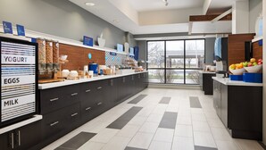 A modern kitchen with a large island, labeled sections for yogurt, eggs, and milk, and a view through large windows. - Holiday Inn Express Hotel & Suites Greenwood by IHG (Greenwood)