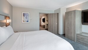 A modern hotel room with a large bed, a flat-screen TV, a wooden wardrobe, and a painting on the wall. - Holiday Inn Express Hotel & Suites Greenwood by IHG (Greenwood)