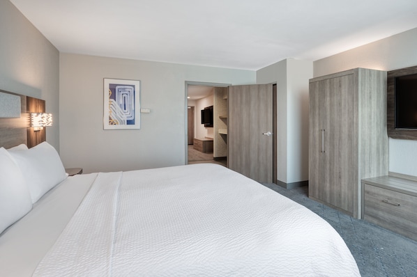 A modern hotel room with a large bed, a flat-screen TV, a wooden wardrobe, and a painting on the wall. - Holiday Inn Express Hotel & Suites Greenwood by IHG (Greenwood)