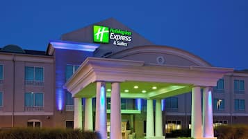 A Holiday Inn Express & Suites hotel with a prominent sign, a covered entrance, and a landscaped front yard.