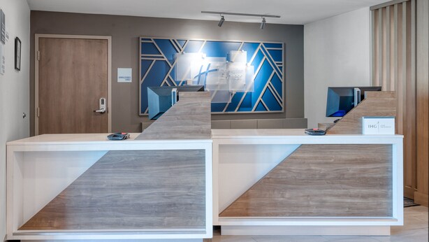 A reception area with a modern design, including a reception desk, a wall-mounted sign, and a door labeled "EMPLOYEES ONLY". - Holiday Inn Express Hotel & Suites Greenwood by IHG (Greenwood)