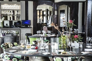A restaurant with round tables set for dining, a bar area with shelves of glasses, and a modern interior design.