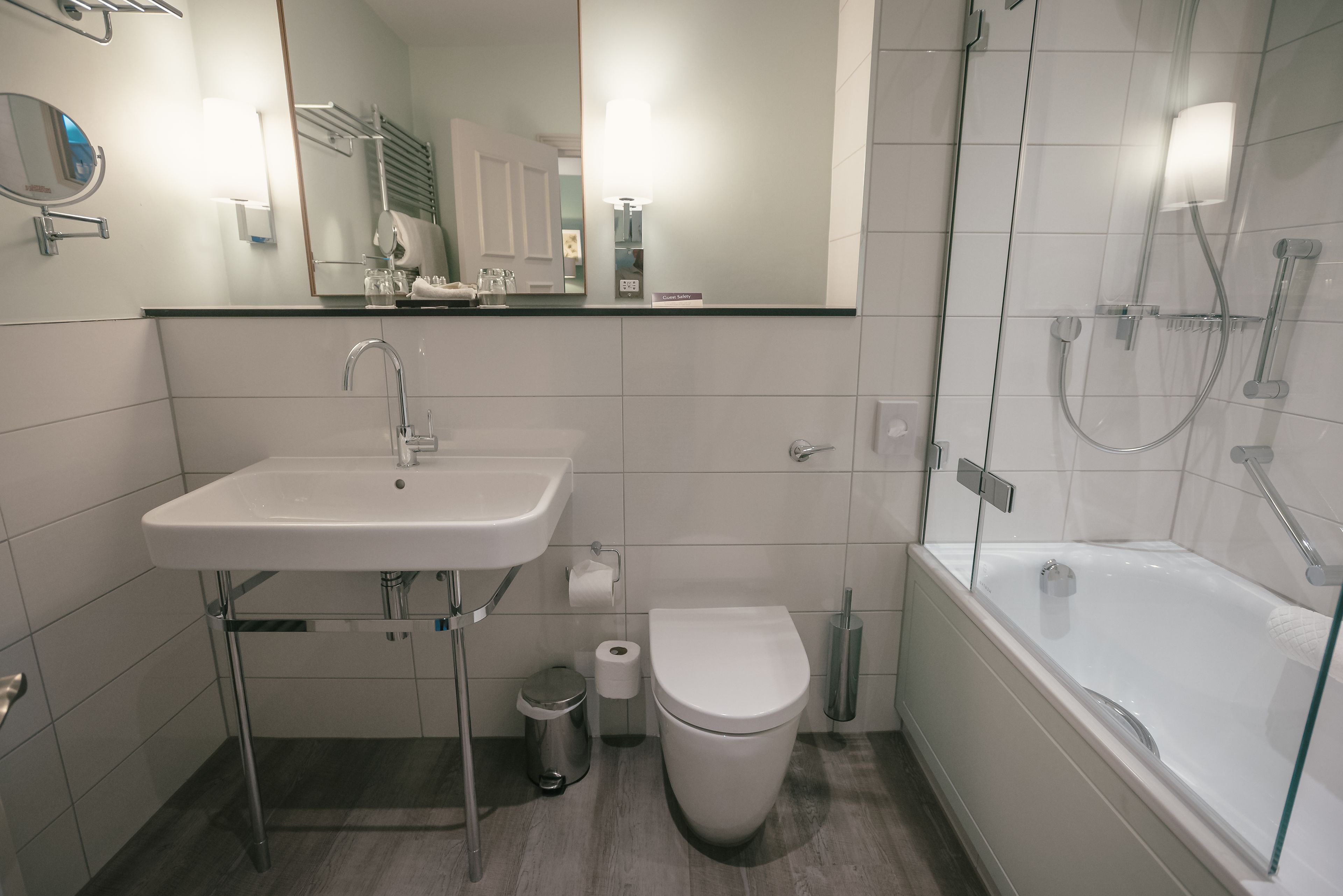 A modern bathroom with a white sink, toilet, and glass-enclosed shower.