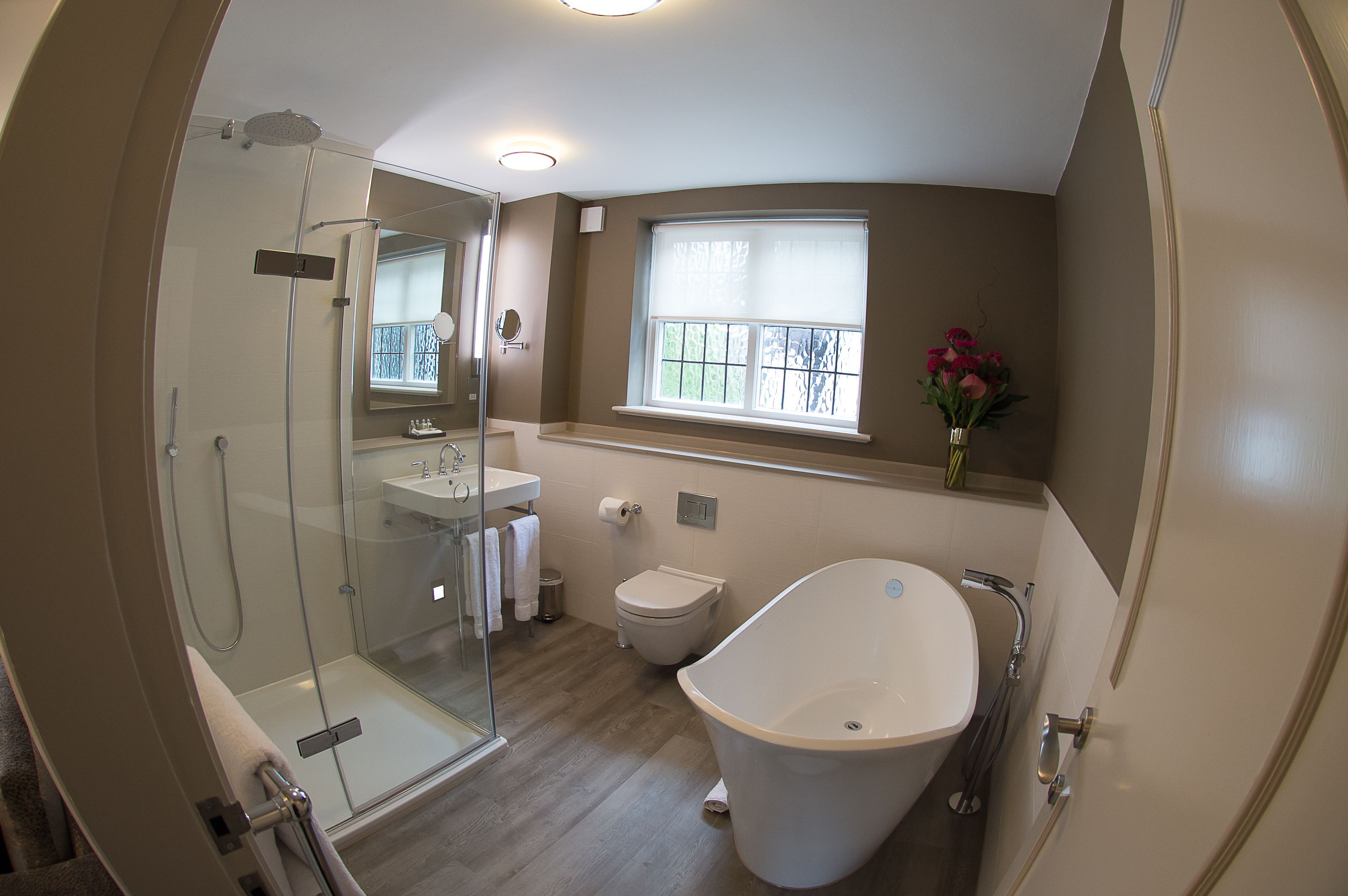 A modern bathroom with a glass-enclosed shower, a freestanding bathtub, and a window with a view.