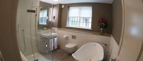 A modern bathroom with a glass-enclosed shower, a freestanding bathtub, and a window with a view.
