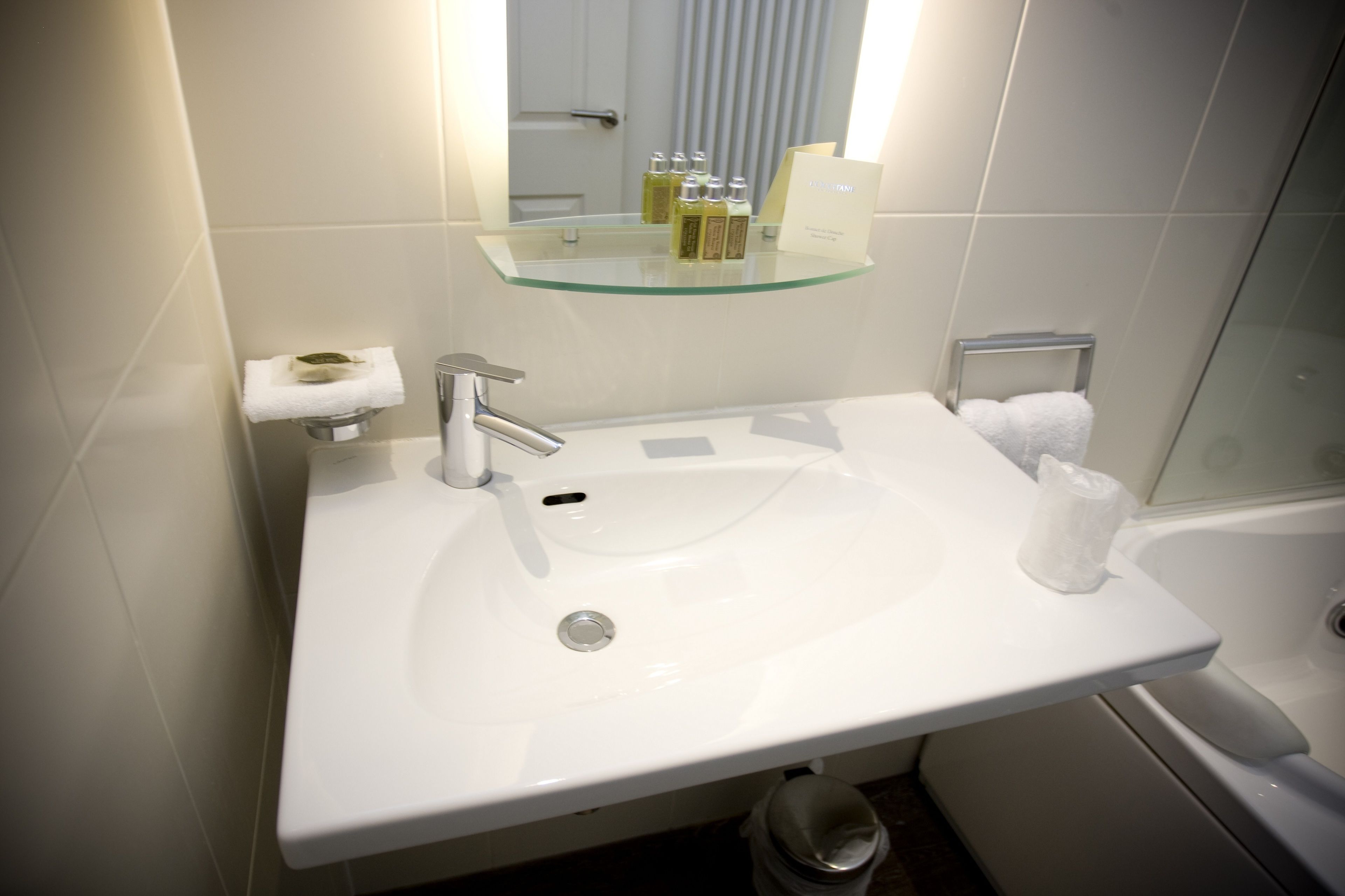 Une salle de bain moderne avec un lavabo blanc, une étagère en verre et une douche à parois de verre.