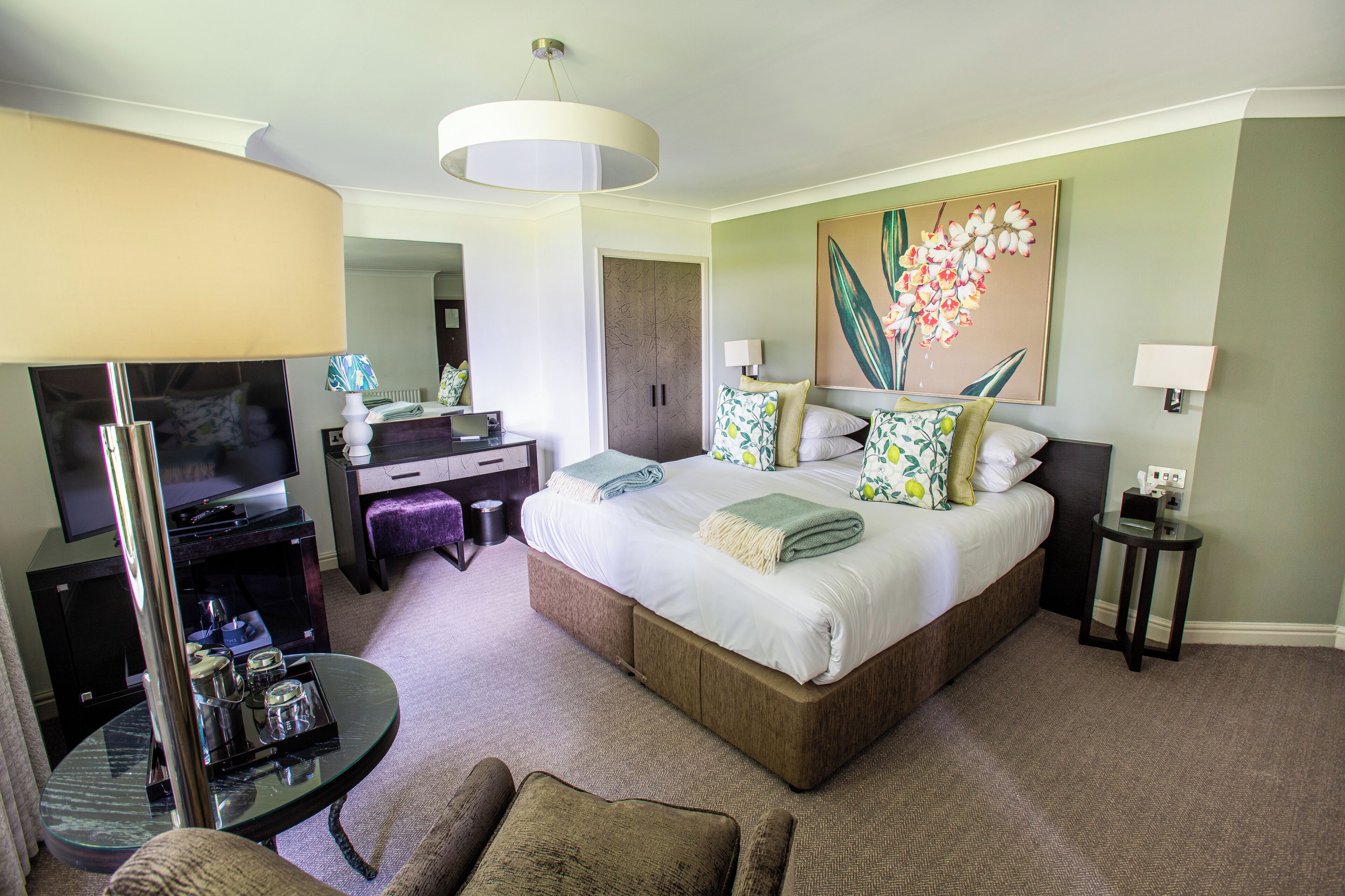 A hotel room with a bed, a TV, a desk, and a chair.