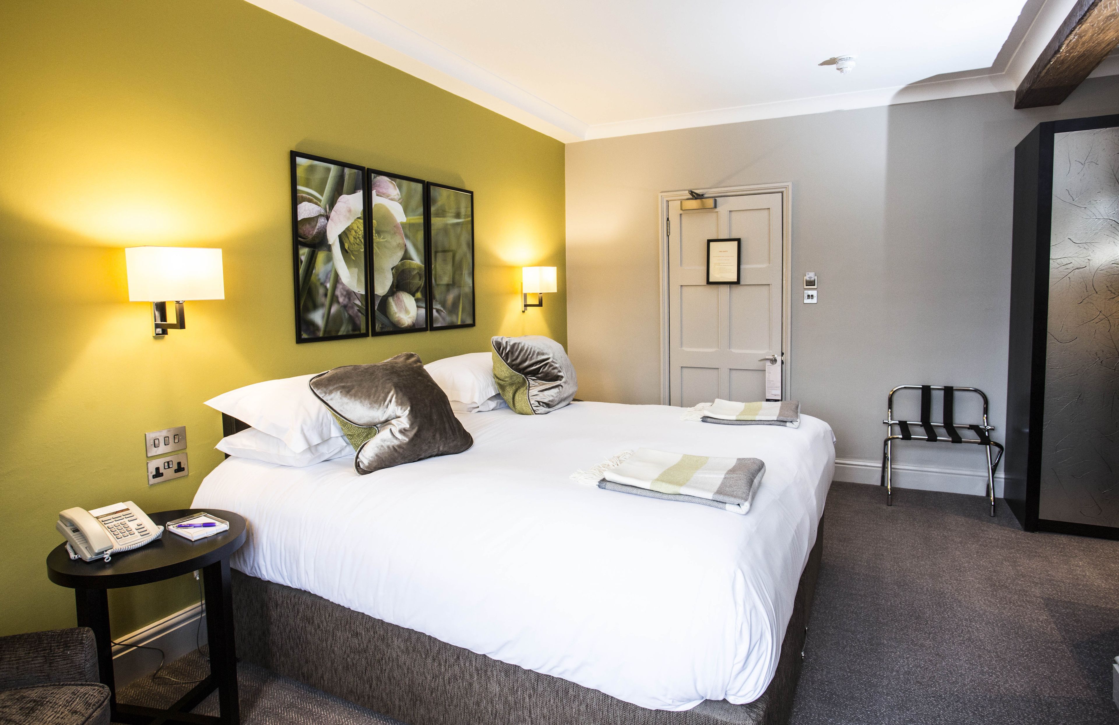 Habitación de hotel con cama, dos lámparas de noche, teléfono y una silla.