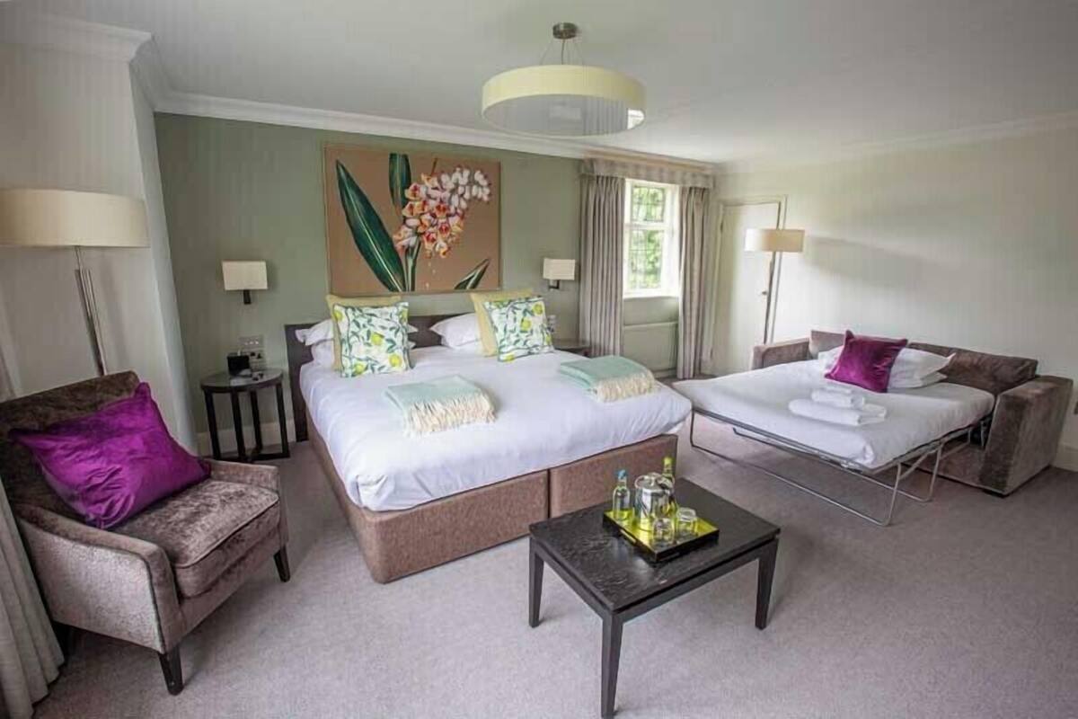 Una habitación de hotel con una cama grande, un sofá, una silla y una mesita.