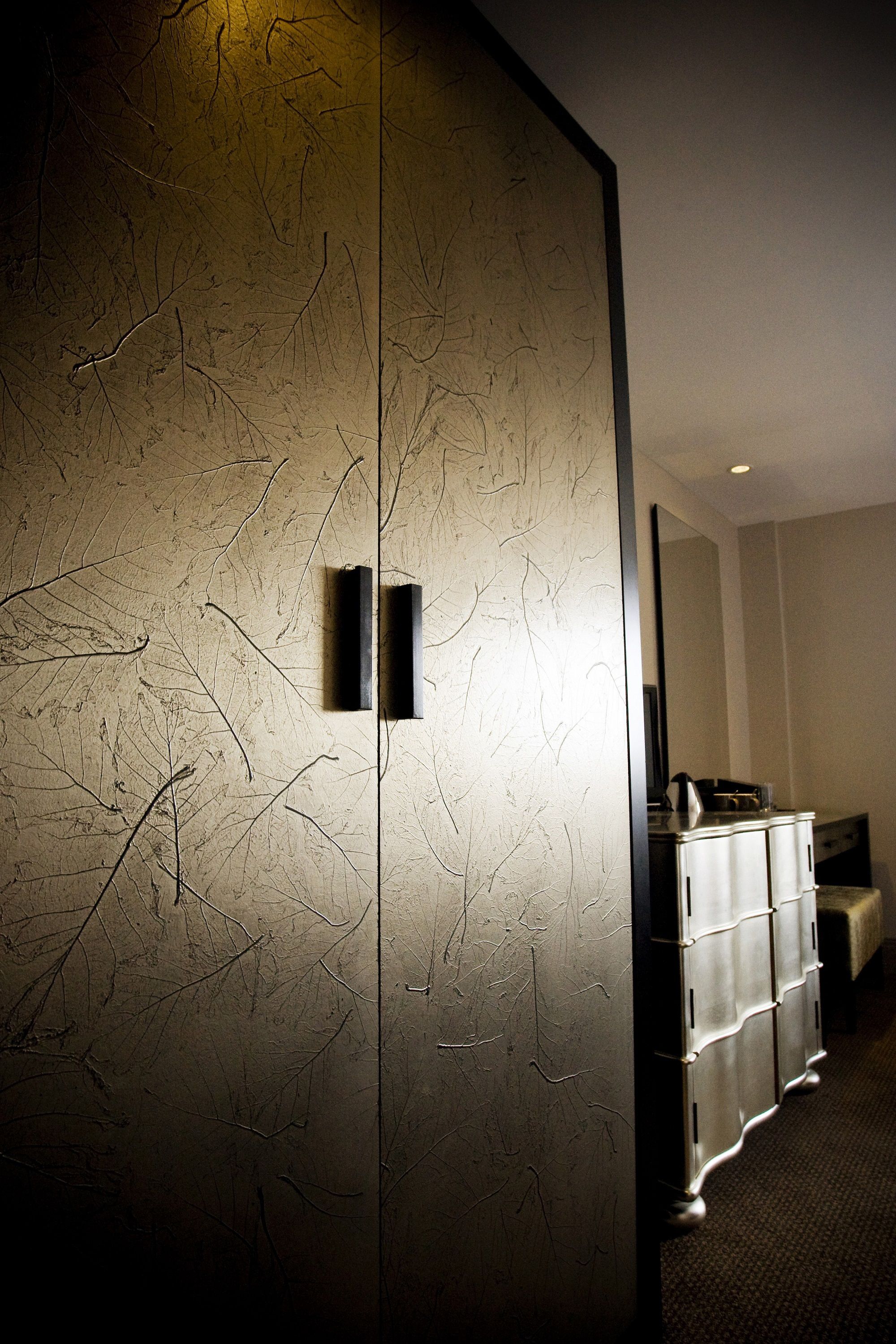Una habitación con pared texturizada, un mueble y un espejo.