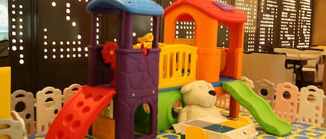 A play area with a train set, a slide, and a table with chairs.