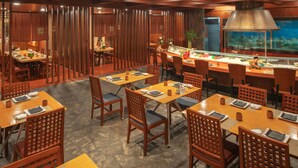 A restaurant with wooden furniture, a sushi bar, and a large fish tank. - Hotel Nikko Dalian (Dalian)