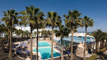 Una piscina al aire libre, sombrillas, sillones reclinables de piscina