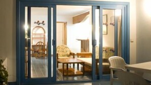 Una habitación con un ventanal corredizo que da a un comedor con una mesa y sillas.