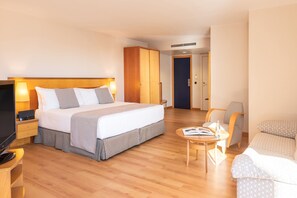 Relax in a spacious room with a large bed, flat-screen TV, and comfortable seating area.
