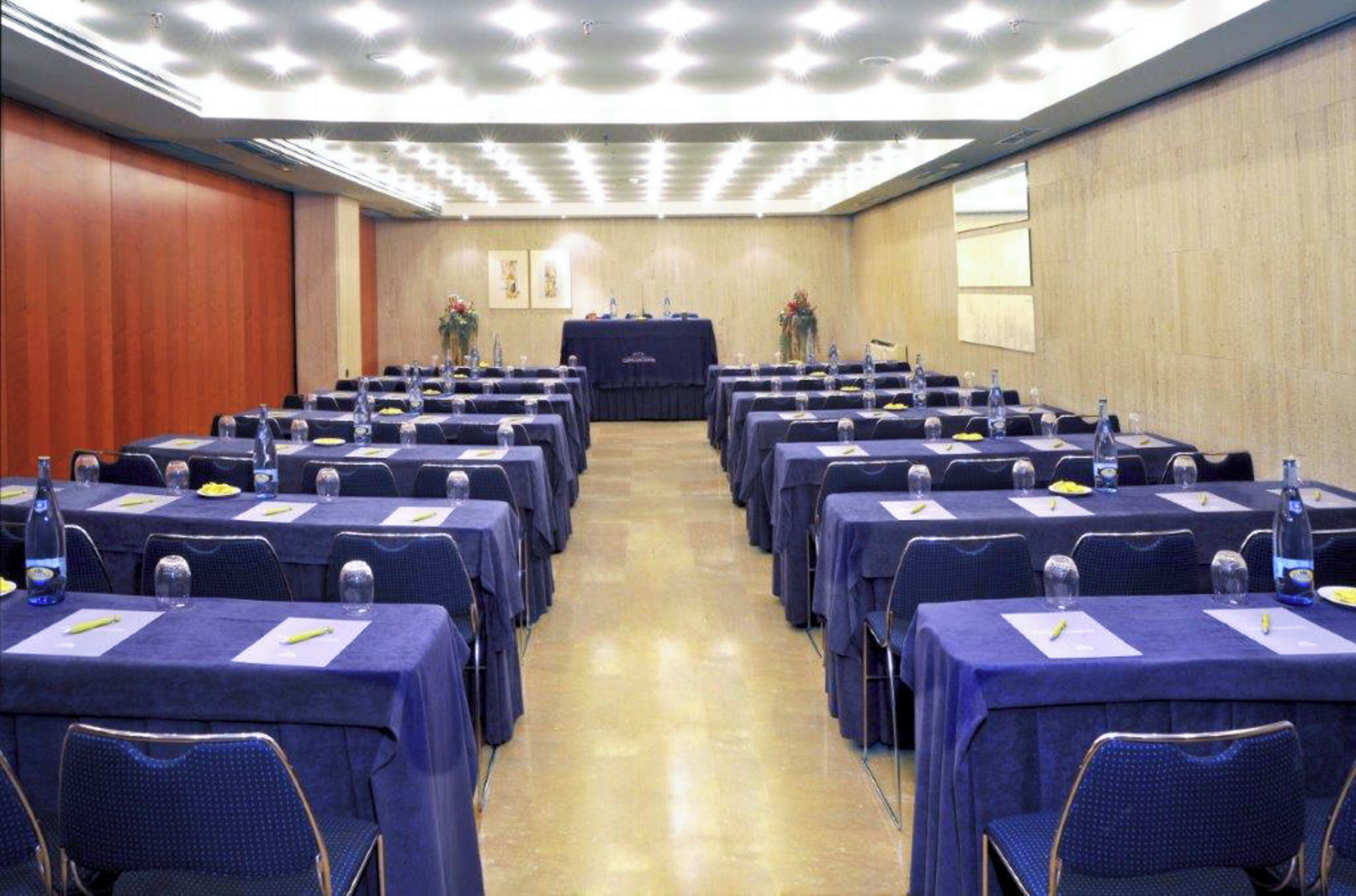 Un salón de conferencias con filas de mesas, sillas y un atril.