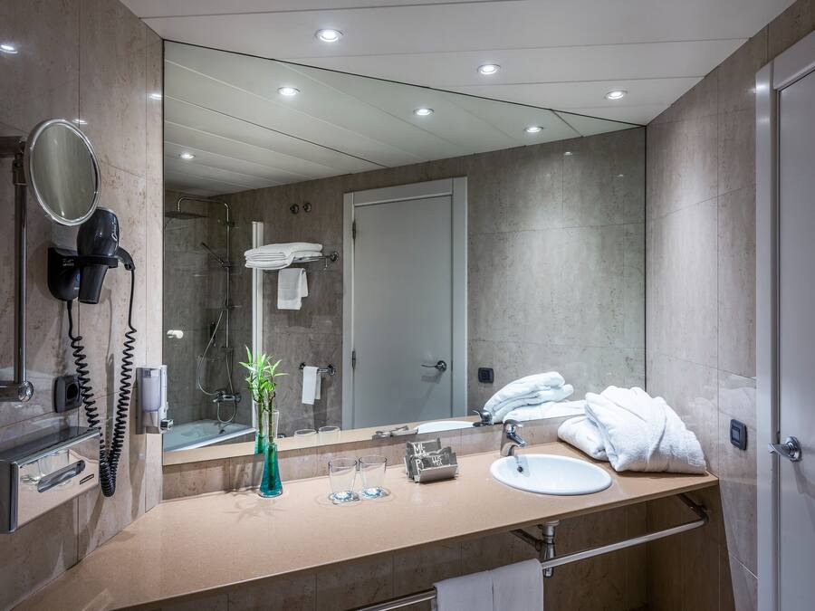 Un baño moderno con un espejo grande, un secador de pelo, un perchero para toallas y un lavamanos.