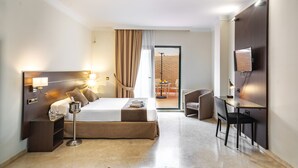 A hotel room with a large bed, bedside table, lamp, and a desk with a chair. - Hotel Mainake (Velez-Malaga)