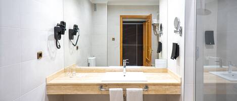 A modern bathroom with a large mirror, a sink, and a shower area.