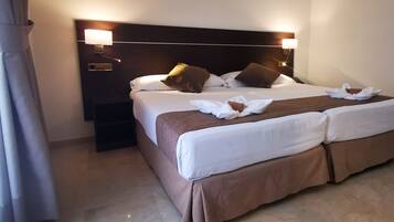 A hotel room with a large bed, two bedside lamps, and a nightstand.